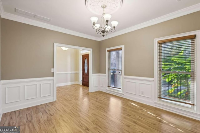 empty room with crown molding, light hardwood / wood-style flooring, and a notable chandelier