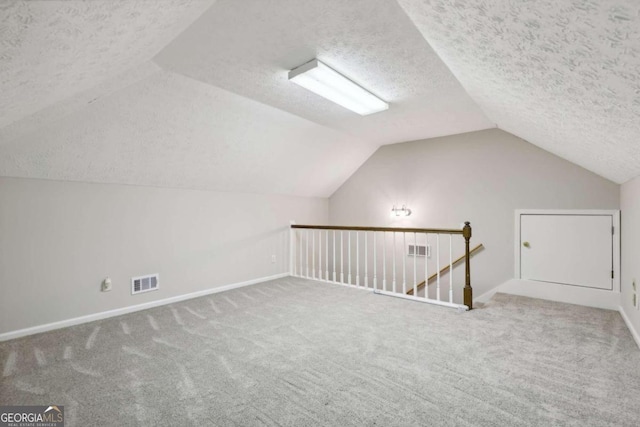 additional living space featuring a textured ceiling, carpet floors, and lofted ceiling