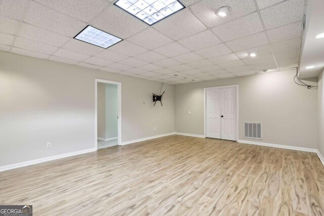 living room featuring a drop ceiling and light hardwood / wood-style flooring