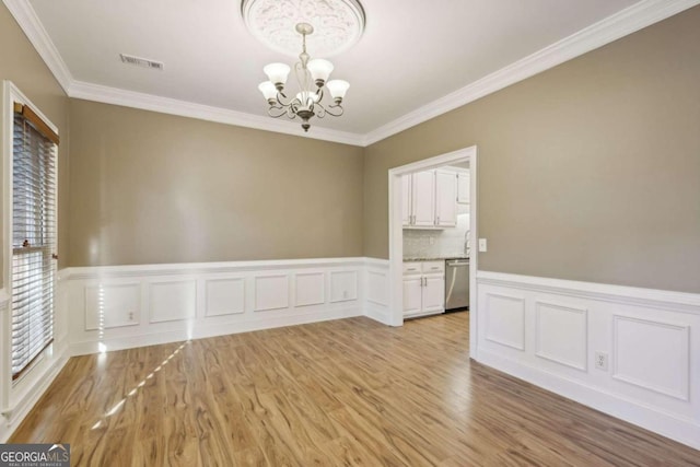 empty room featuring an inviting chandelier, light hardwood / wood-style flooring, and ornamental molding