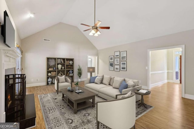 living room featuring ceiling fan, high vaulted ceiling, and light wood-type flooring