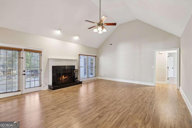 unfurnished living room with ceiling fan, light hardwood / wood-style floors, and high vaulted ceiling