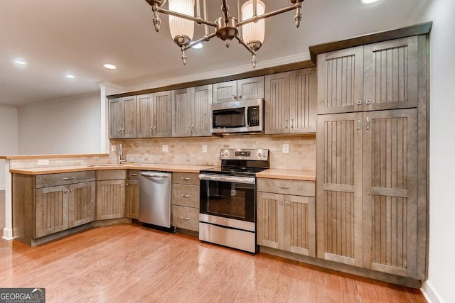 kitchen with sink, backsplash, light hardwood / wood-style floors, appliances with stainless steel finishes, and ornamental molding