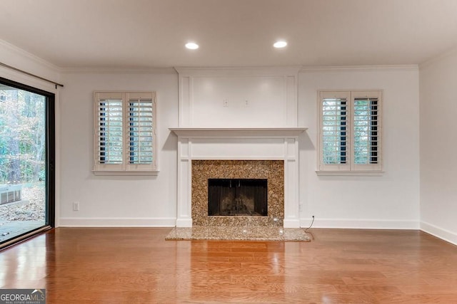 unfurnished living room featuring a fireplace, hardwood / wood-style flooring, and crown molding