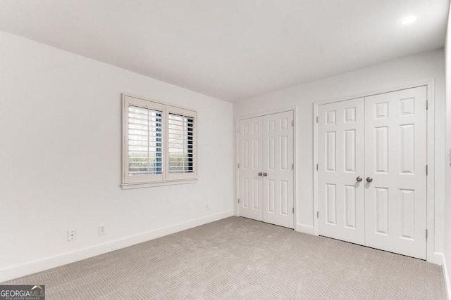 unfurnished bedroom featuring two closets and light colored carpet