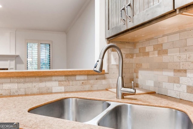 room details featuring decorative backsplash, crown molding, and sink