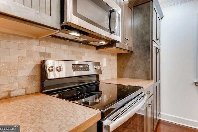 kitchen with backsplash, dark hardwood / wood-style flooring, ornamental molding, and stainless steel appliances