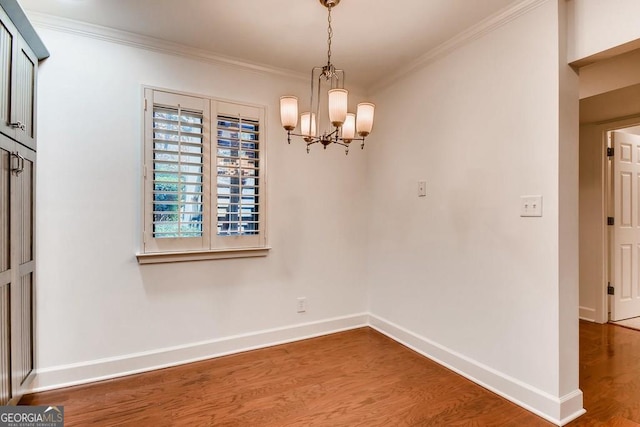 unfurnished dining area with wood-type flooring, an inviting chandelier, and crown molding