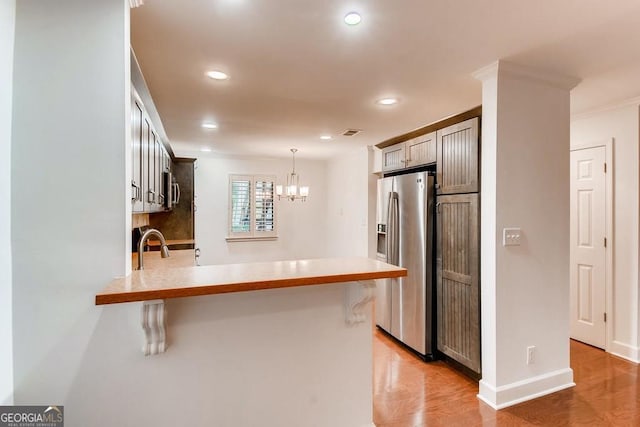 kitchen featuring a kitchen breakfast bar, crown molding, kitchen peninsula, and stainless steel refrigerator with ice dispenser