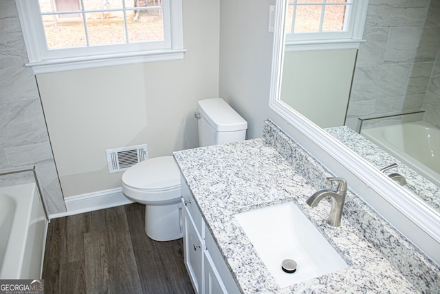 bathroom with hardwood / wood-style floors, plenty of natural light, toilet, and vanity