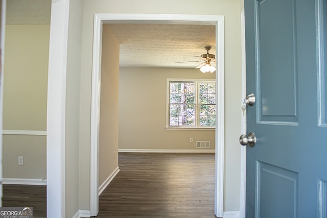 hall with a textured ceiling and dark wood-type flooring