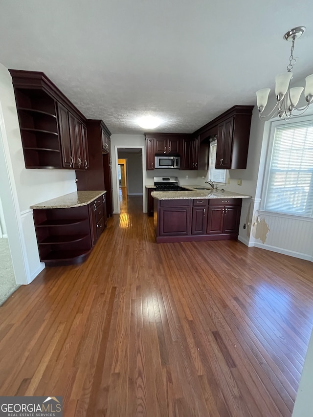 kitchen featuring appliances with stainless steel finishes, dark hardwood / wood-style flooring, dark brown cabinets, and pendant lighting