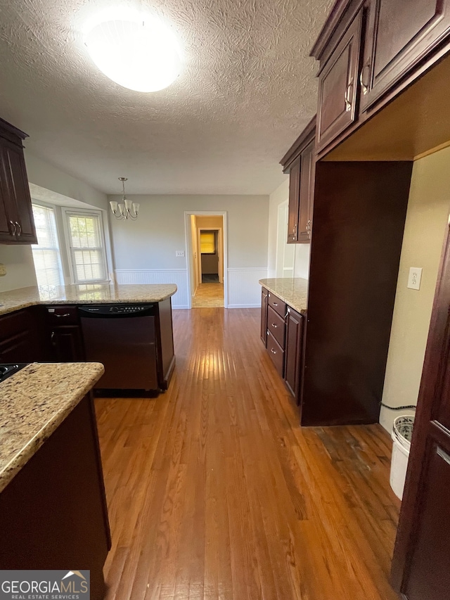 kitchen with dark brown cabinets, light hardwood / wood-style floors, stainless steel dishwasher, and hanging light fixtures