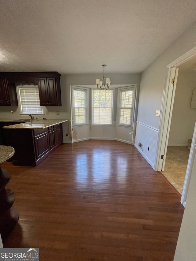 kitchen with dark brown cabinetry, sink, hanging light fixtures, dark hardwood / wood-style floors, and a notable chandelier