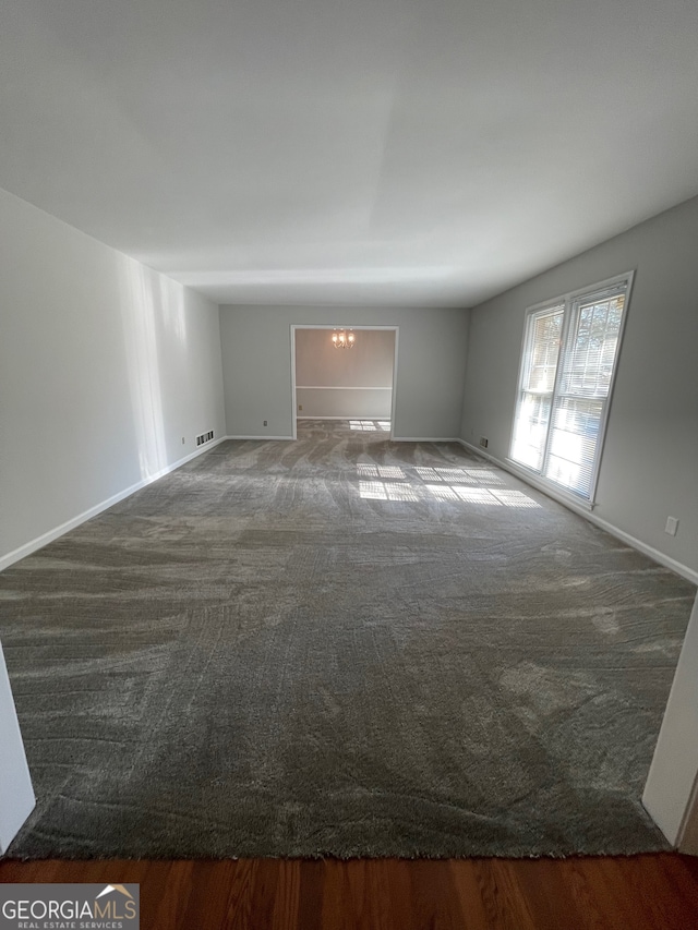 carpeted empty room with a chandelier