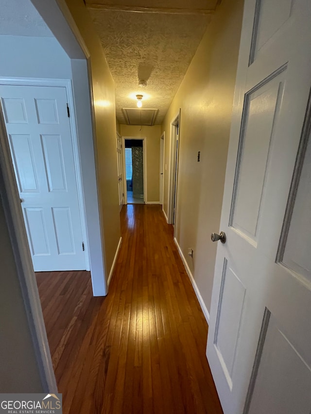 hall with a textured ceiling and dark hardwood / wood-style flooring