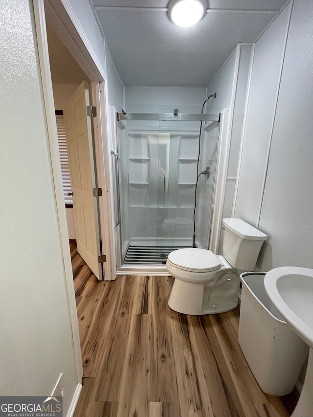 bathroom with toilet, wood-type flooring, and walk in shower