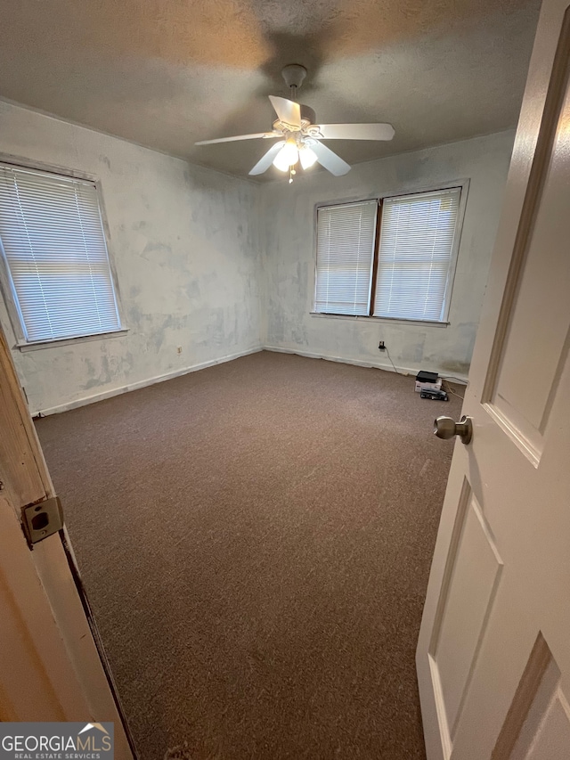 empty room with ceiling fan, carpet floors, and a textured ceiling