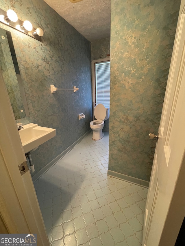 bathroom featuring tile patterned flooring, sink, toilet, and a textured ceiling