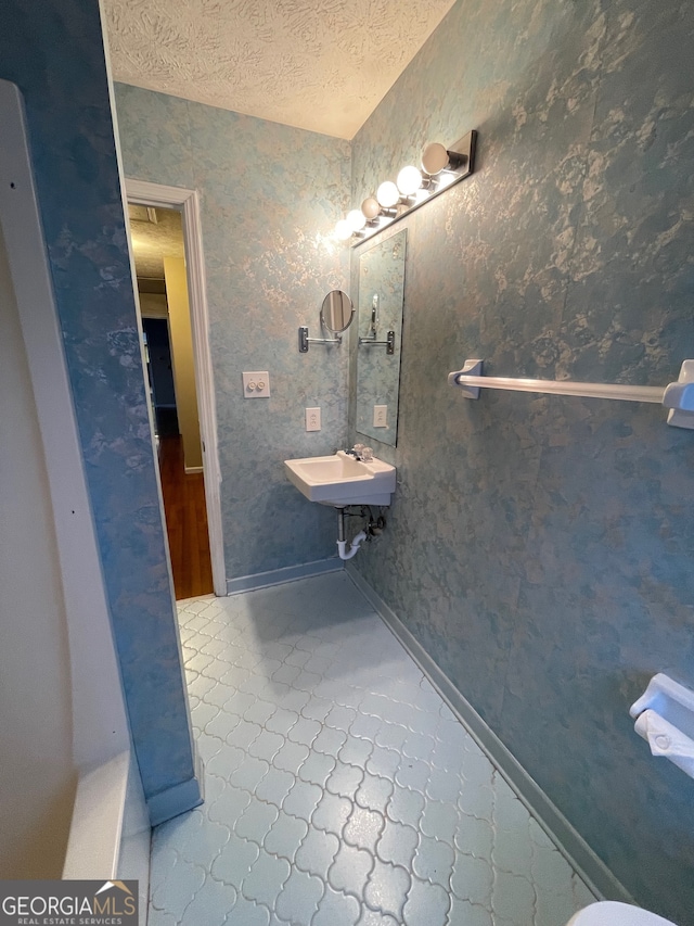 bathroom with a textured ceiling, tile patterned floors, and sink