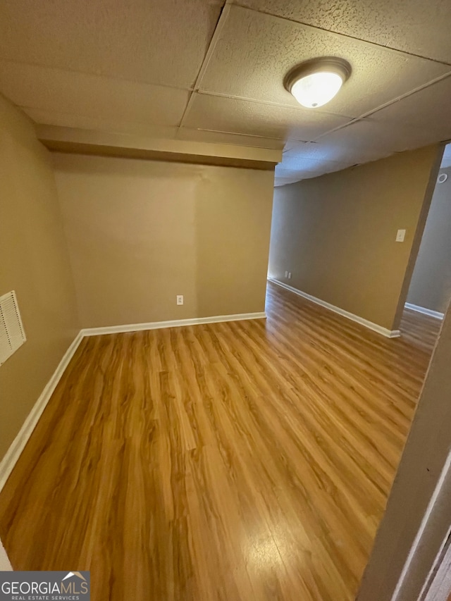 basement featuring hardwood / wood-style flooring and a paneled ceiling