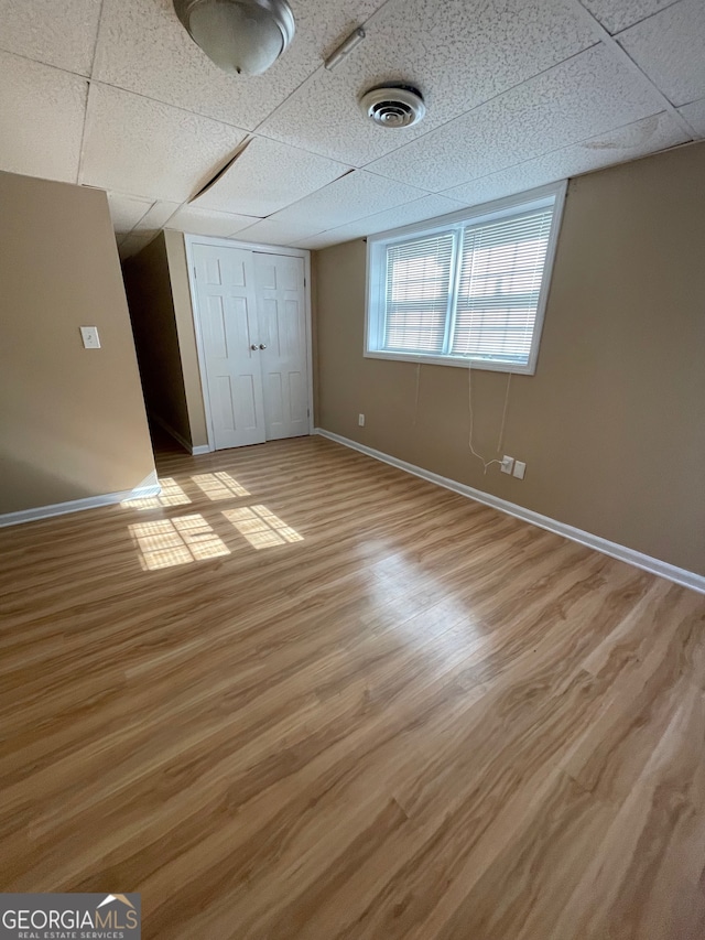 unfurnished bedroom featuring light wood-type flooring, a closet, and a paneled ceiling