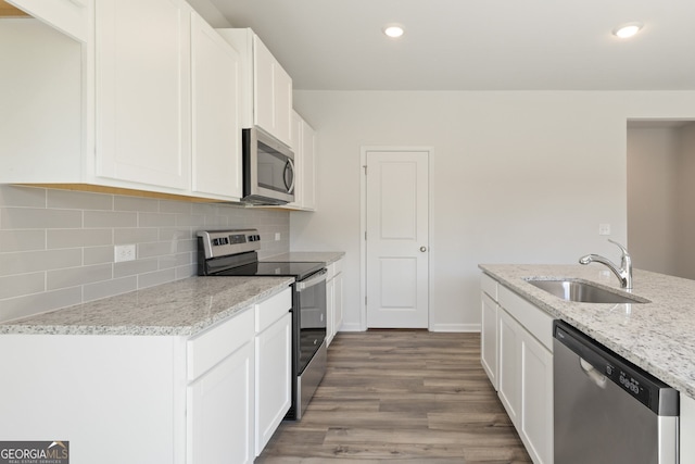 kitchen with stainless steel appliances, tasteful backsplash, white cabinets, a sink, and light stone countertops