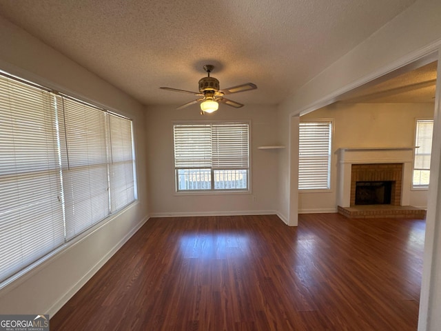 unfurnished living room with a textured ceiling, a fireplace, ceiling fan, and dark wood-type flooring