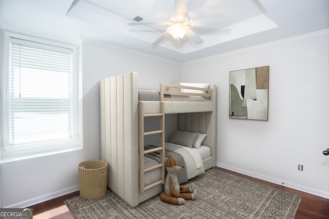 bedroom with a raised ceiling, ornamental molding, and dark wood-type flooring