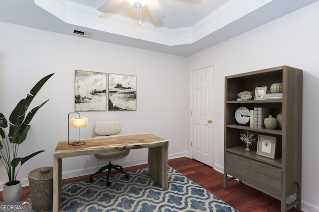 office featuring dark hardwood / wood-style floors, built in features, ornamental molding, ceiling fan, and a raised ceiling