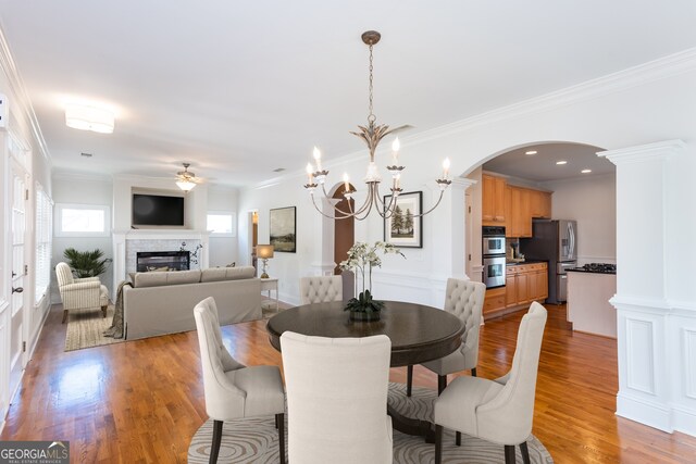 unfurnished living room with a fireplace, ceiling fan, dark hardwood / wood-style flooring, and ornamental molding