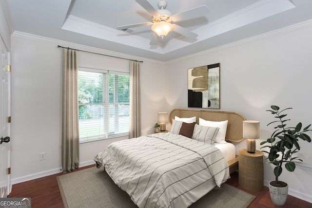 bedroom featuring a tray ceiling, ornamental molding, dark hardwood / wood-style floors, and ceiling fan