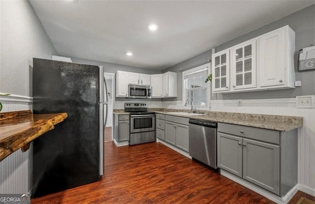 kitchen with appliances with stainless steel finishes, sink, white cabinets, gray cabinets, and dark hardwood / wood-style floors