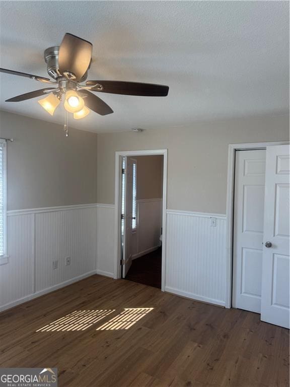 empty room with dark hardwood / wood-style floors, ceiling fan, and a textured ceiling