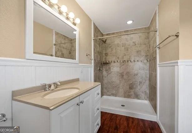 bathroom with hardwood / wood-style floors, vanity, and a tile shower