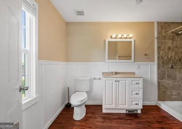 bathroom with tiled shower, hardwood / wood-style floors, vanity, and toilet