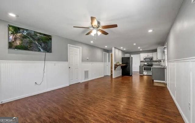 unfurnished living room featuring ceiling fan, sink, and dark wood-type flooring