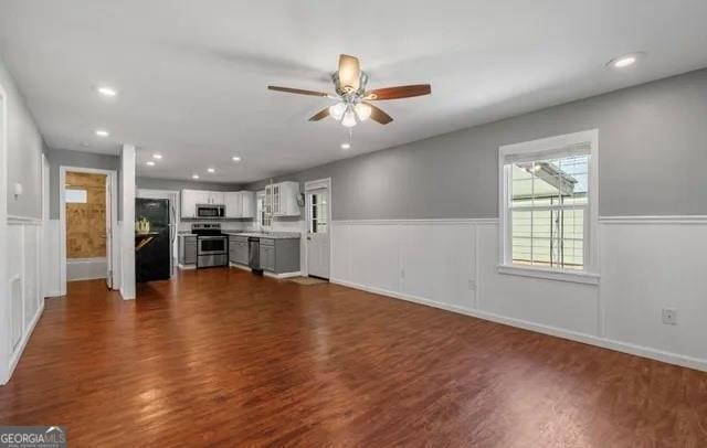 unfurnished living room featuring ceiling fan and dark hardwood / wood-style floors