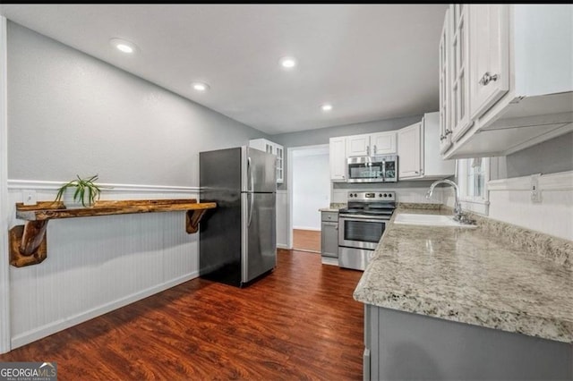 kitchen featuring light stone countertops, white cabinetry, sink, dark wood-type flooring, and appliances with stainless steel finishes