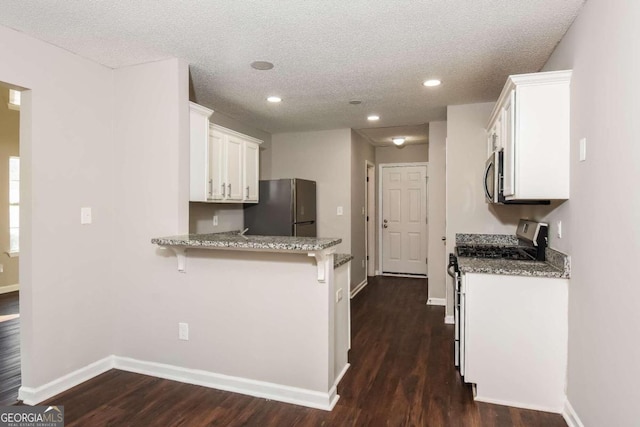 kitchen with kitchen peninsula, appliances with stainless steel finishes, stone counters, dark hardwood / wood-style floors, and white cabinetry