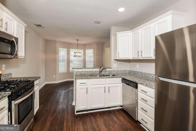 kitchen with dark hardwood / wood-style floors, white cabinetry, kitchen peninsula, and appliances with stainless steel finishes