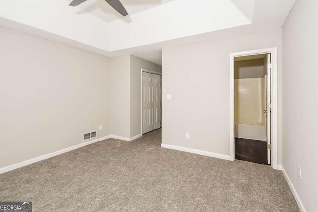 unfurnished bedroom featuring carpet, ceiling fan, connected bathroom, and a closet