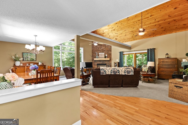 living room with vaulted ceiling, a stone fireplace, light hardwood / wood-style flooring, and a textured ceiling