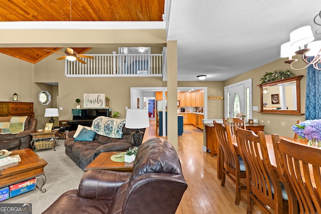 living room with lofted ceiling with beams, light wood-type flooring, and ceiling fan with notable chandelier