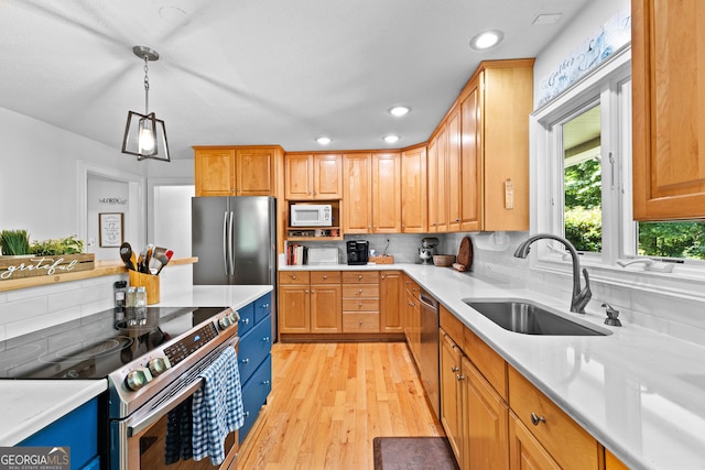 kitchen featuring pendant lighting, sink, light wood-type flooring, appliances with stainless steel finishes, and tasteful backsplash