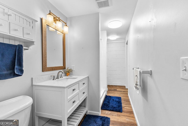 bathroom featuring walk in shower, toilet, vanity, and hardwood / wood-style flooring