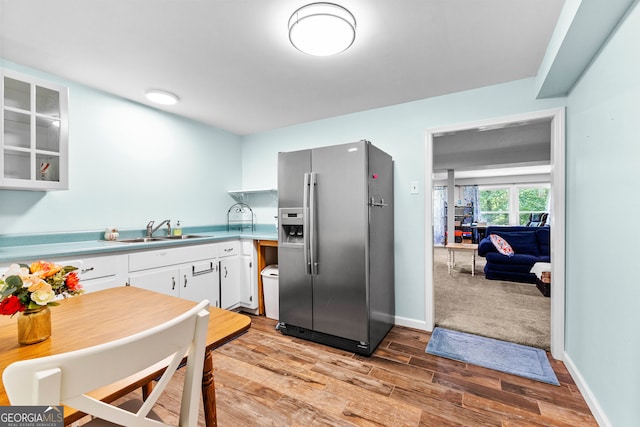 kitchen with stainless steel fridge with ice dispenser, sink, white cabinets, and light hardwood / wood-style floors