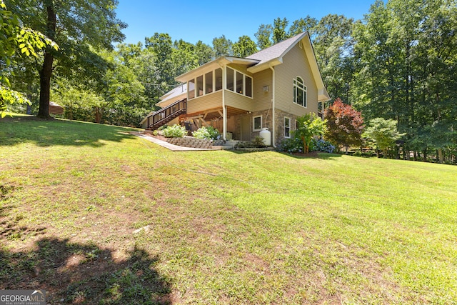 rear view of house with a lawn and a sunroom