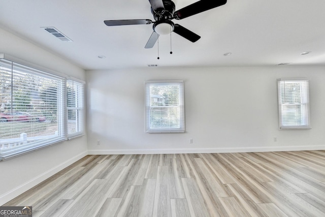 empty room with plenty of natural light, light hardwood / wood-style floors, and ceiling fan