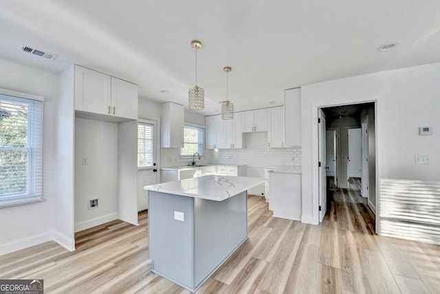 kitchen featuring pendant lighting, light hardwood / wood-style flooring, white cabinets, and a kitchen island